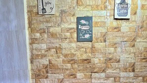 Una mesa de madera rústica con cuatro taburetes a juego, frente a una pared de piedra decorada con motivos de cocina.