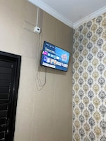 Un televisor montado en una pared con textura y un diseño de papel tapiz estampado.