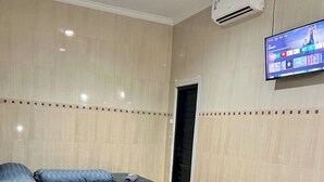 Una habitación de hotel con una cama grande, un televisor de pantalla plana en la pared y un equipo de aire acondicionado.