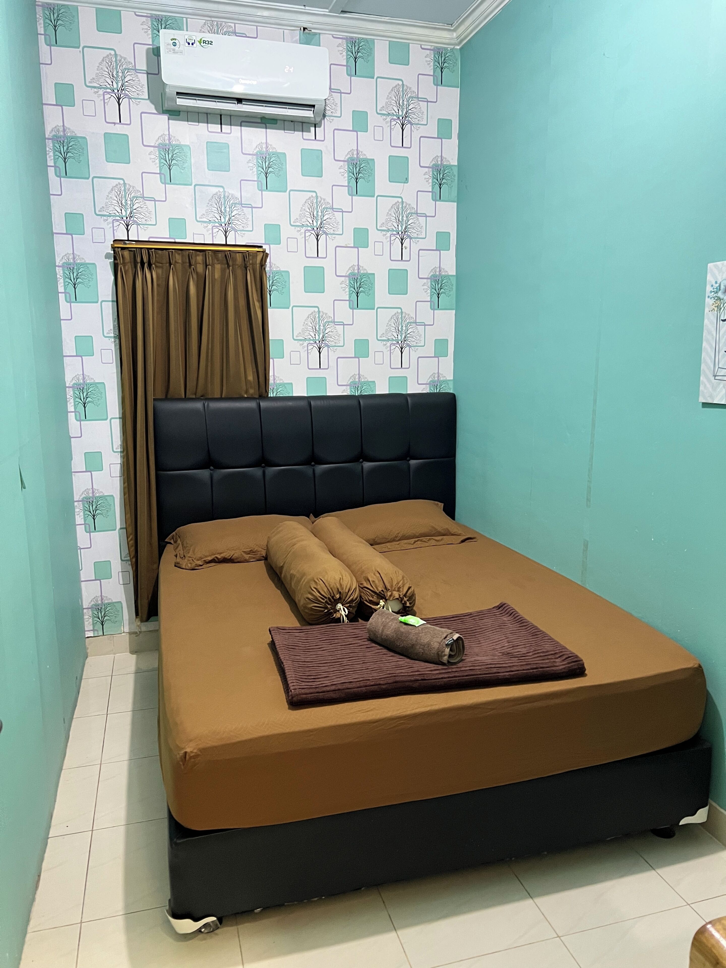 A room with a bed, a curtain, a wall air conditioner, and a patterned wallpaper.