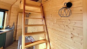 A wooden interior with a spiral staircase, a dining area, and a kitchen with a dishwasher.