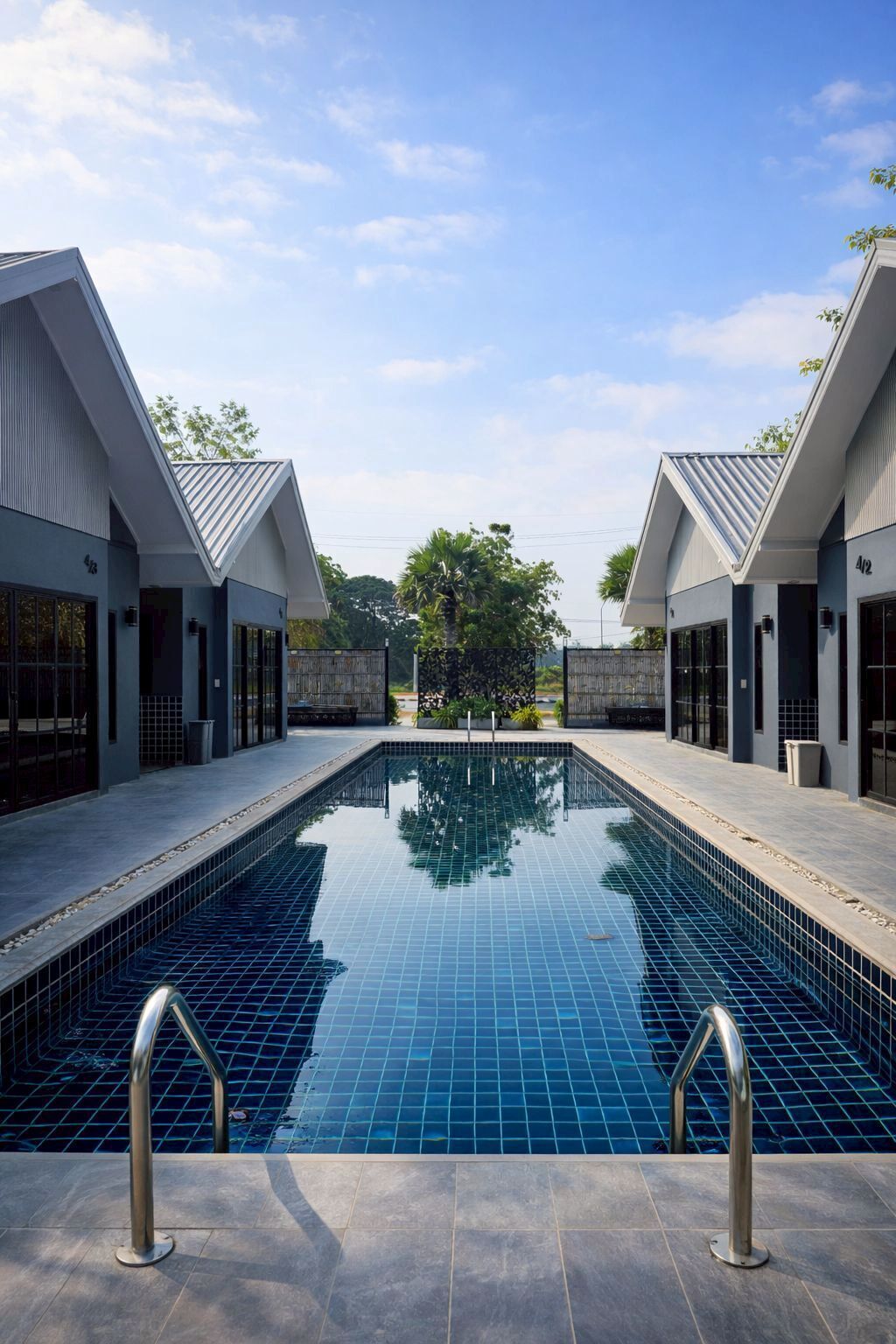 Un hotel moderno con piscina central, edificios de dos pisos y cielo despejado.