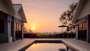 Una piscina con vista sul tramonto, circondata da edifici moderni.