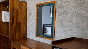 Una stanza con una scrivania in legno, uno specchio, un armadio e un frigorifero.