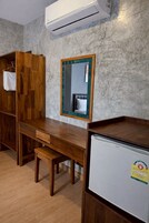 Una habitación con escritorio de madera, espejo, armario y refrigerador.