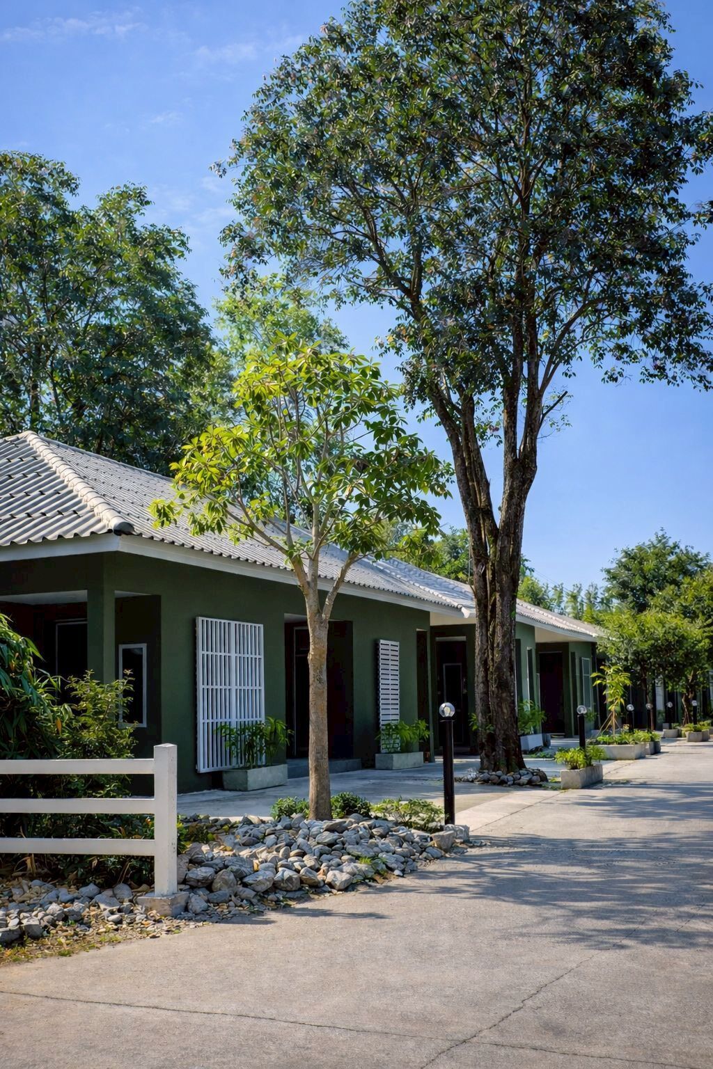 A building with a green facade, white shutters, and a tiled roof.