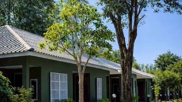 A building with a green facade, white shutters, and a tiled roof.