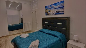 A bedroom with a bed, a nightstand, a mirror, and a painting. - Cozy vacation home in the heart of the historic center of Naples (Napoli)