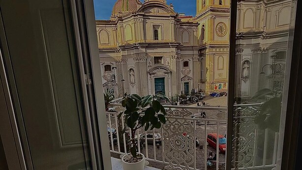 A balcony with a view of a historic building with domes and a clock. - Cozy vacation home in the heart of the historic center of Naples (Napoli)