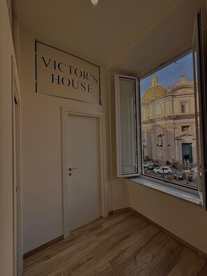 A hallway with a sign reading 'VICTOR'S HOUSE,' a door, and a window with a view of a building. - Cozy vacation home in the heart of the historic center of Naples (Napoli)