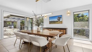 Eine moderne Küche mit einem großen Holztisch, weißen Stühlen und Blick ins Freie.