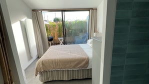 Une chambre à coucher avec un lit, une chaise, une table et une vue sur l’extérieur.