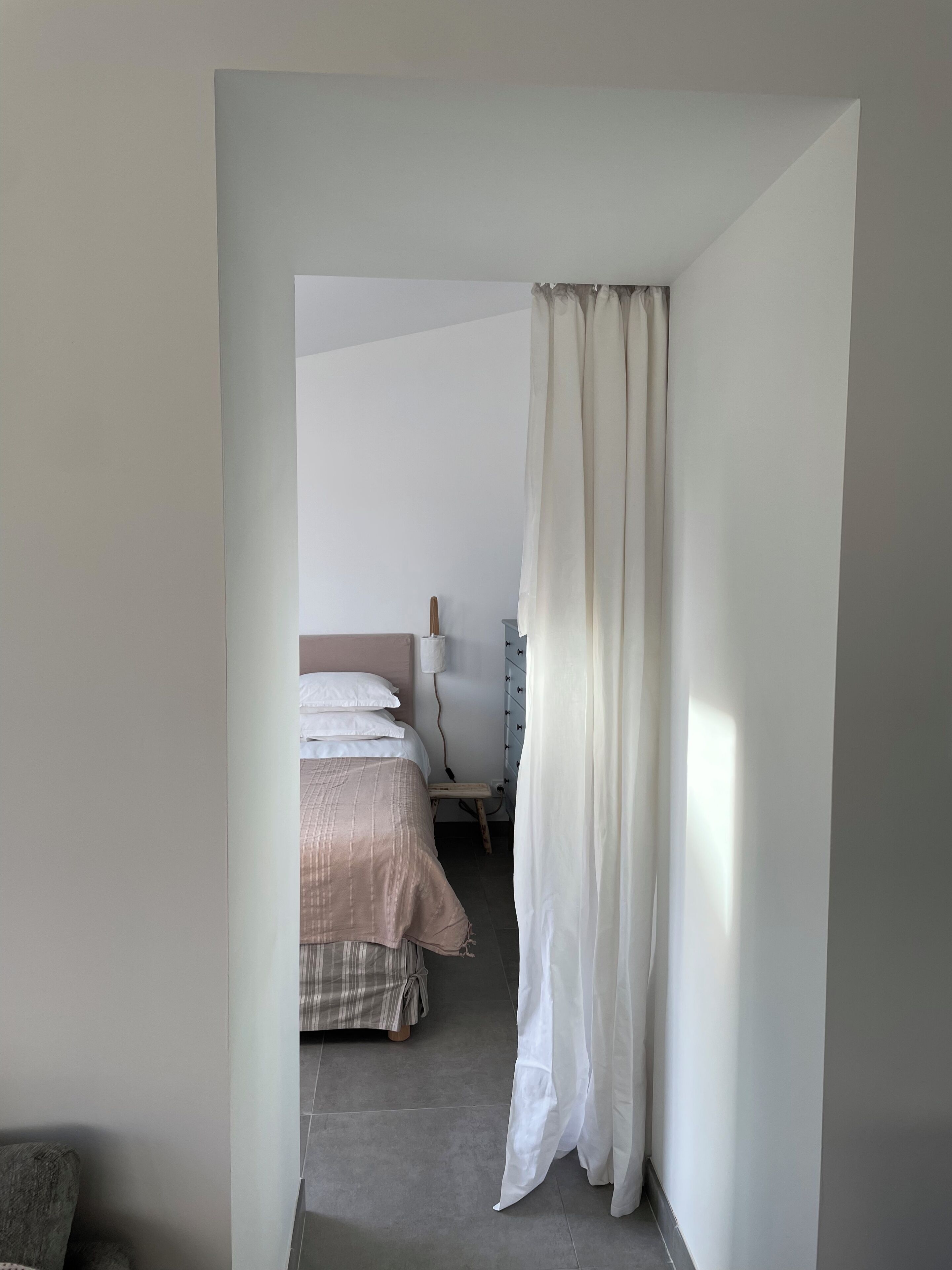 Une chambre à coucher avec un lit, une table de chevet et un rideau.