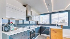 A modern kitchen with a large window, built-in oven, and a coffee machine. - Incredible 3BR Battersea Flat & Spectacular View (Greater London)