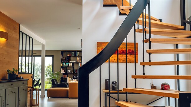 A modern staircase with wooden steps and black metal railings. - Bread et Couette (Lyon)