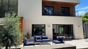 A modern two-story house with a balcony, large windows, and outdoor seating. - Bread et Couette (Lyon)