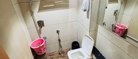 A bathroom with a toilet, bidet, sink, mirror, and a shower.