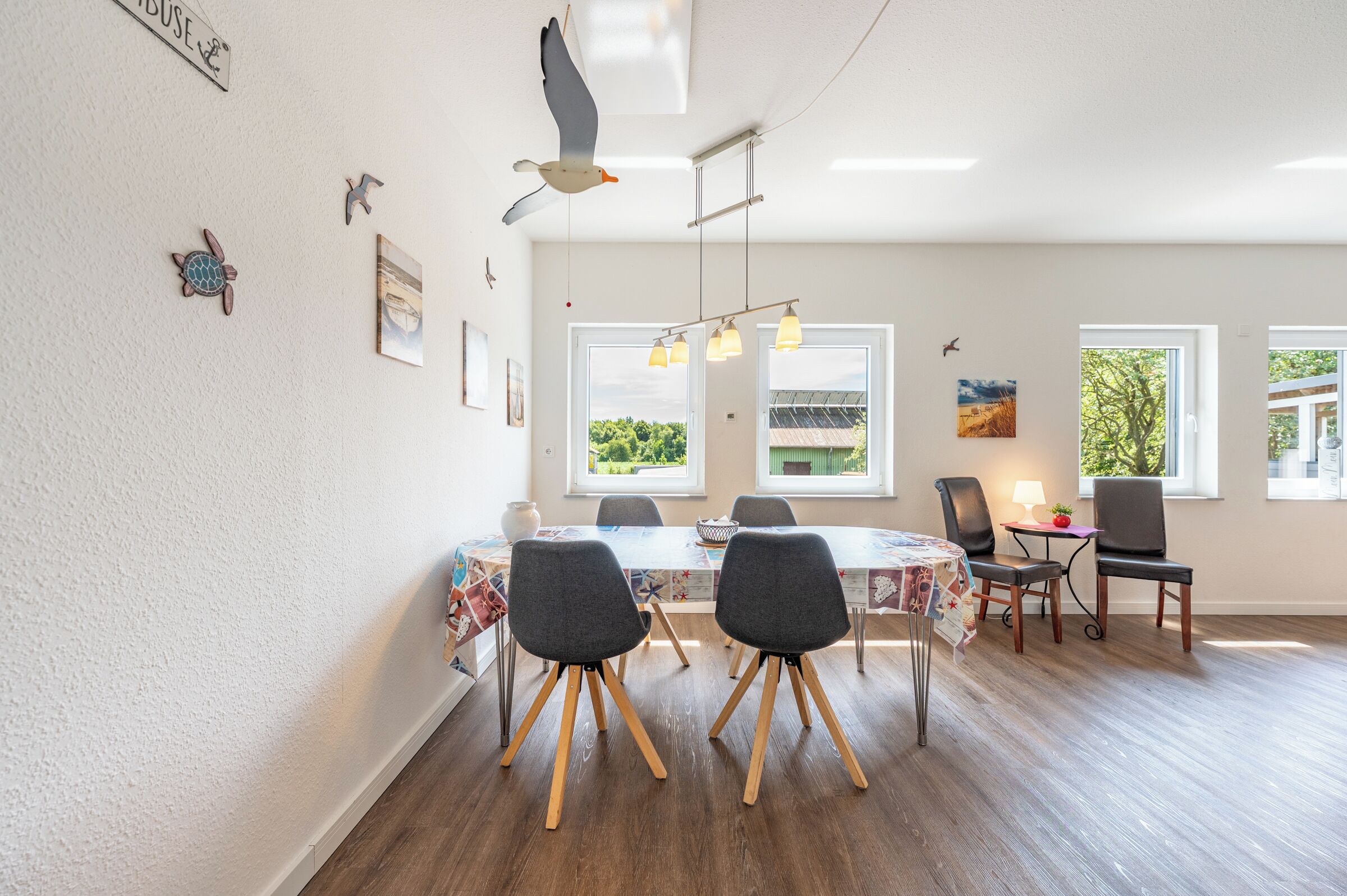 Un espace repas comprenant une table, des chaises et donnant sur un paysage verdoyant.