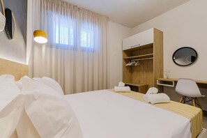 A hotel room with a bed, a desk, a chair, a wardrobe, and a mirror. - DeMar No 3 by RentalsPro - Agios Nikolaos (Agios Nikolaos)