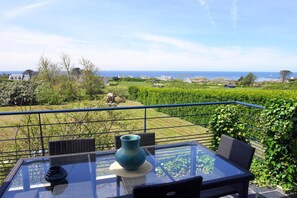 Een balkon met een glazen tafel, stoelen en een vaas.