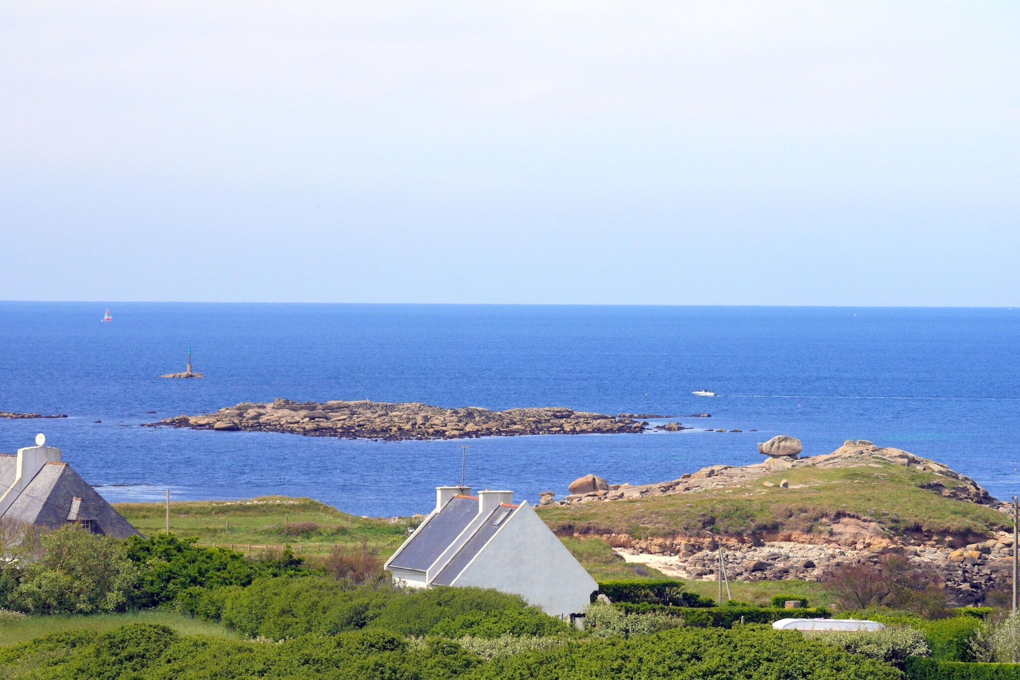 Paisatge costaner amb una casa, roques i la mar.