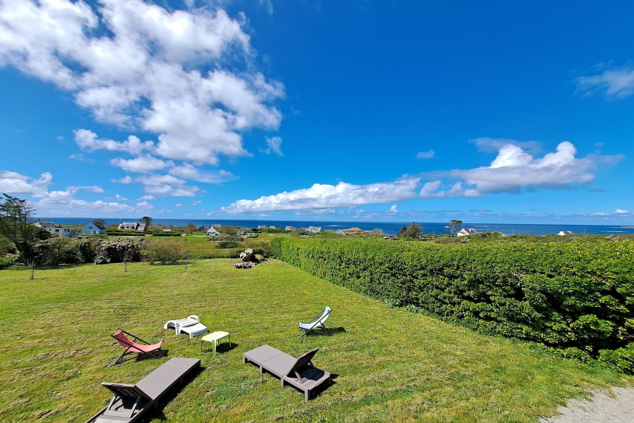A grassy outdoor area with lounge chairs and a view of the sea.