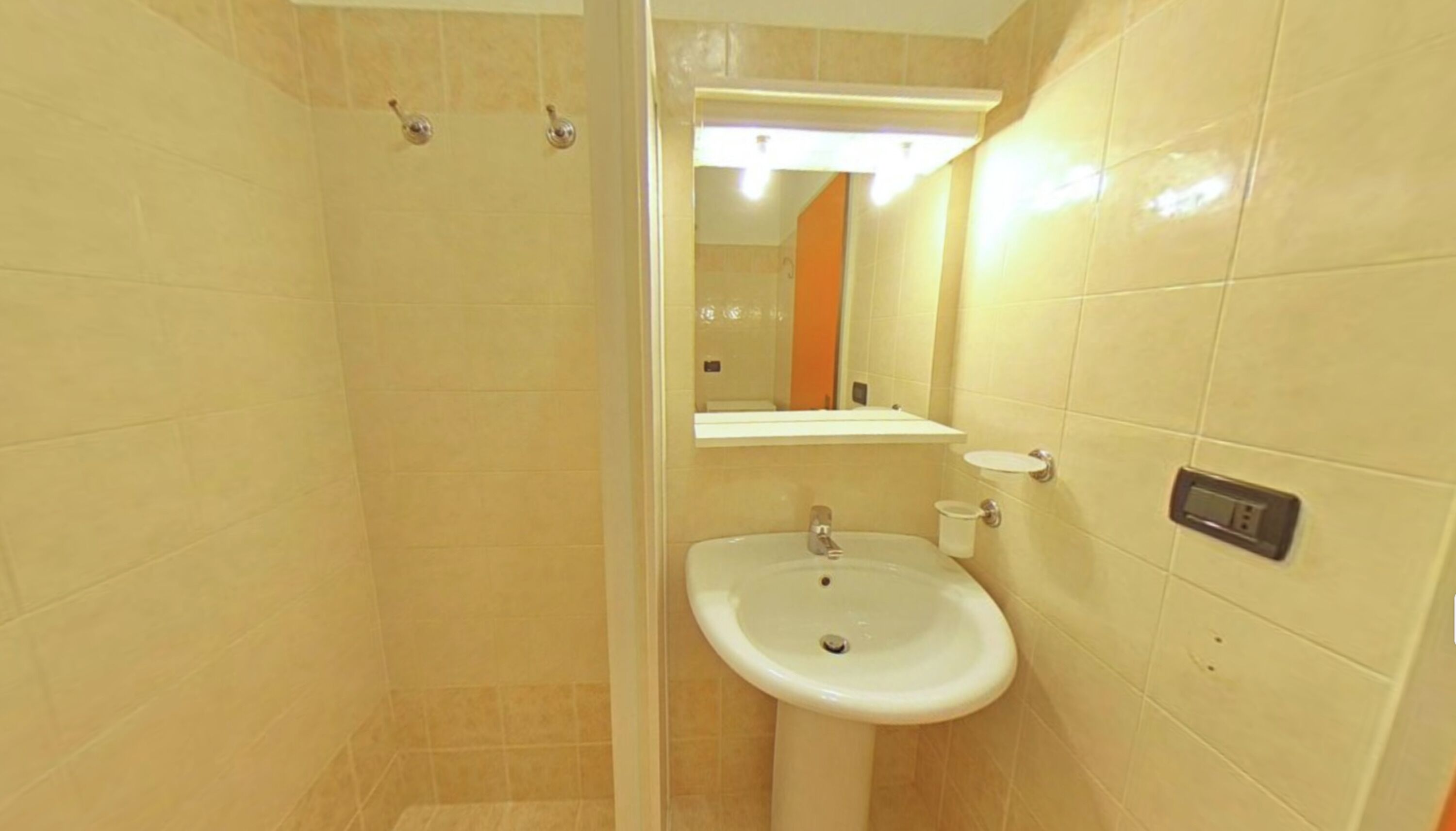 A bathroom with a sink, mirror, and shower.