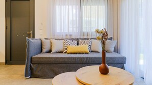 Una habitación con un sofá gris, una mesa redonda de madera y un jarrón con flores.