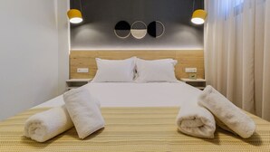 Habitación de hotel con una cama, dos mesitas de noche, cabecera y una lámpara fijada a la pared.