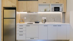 Una cocina moderna con armarios de madera, un refrigerador de acero inoxidable, un microondas y una tetera.