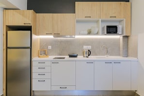 Eine moderne Küche mit Holzausstattung, einem Edelstahlkühlschrank, einer Mikrowelle und einem Wasserkocher.