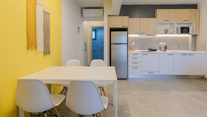 Una cocina moderna con armarios blancos, microondas integrado y refrigerador de acero inoxidable.