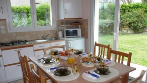 Eine Küche mit Esstisch, gedeckt für das Frühstück, einer Mikrowelle und Blick auf den Garten.