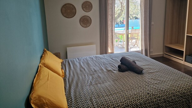 A bedroom with a bed, a wardrobe, and a view of an outdoor area. - Villa "Laurent" with Private Pool Near Lyon (Charly)
