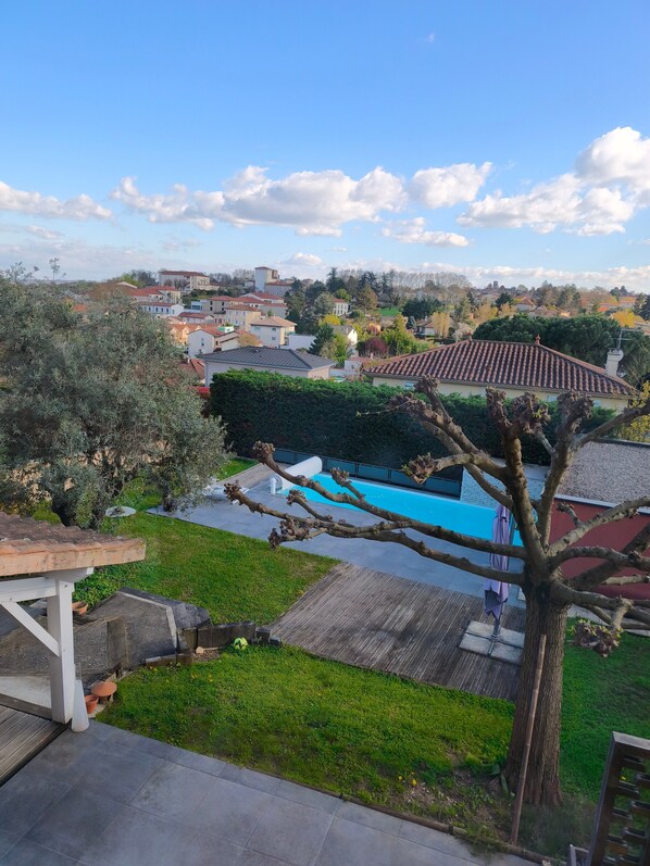 A residential area with a swimming pool, a tree, and a view of houses in the background.
