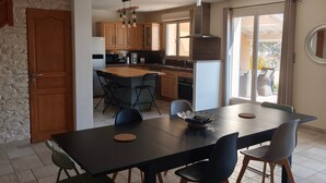 A modern kitchen with wooden cabinets, a dining area with a large table and chairs, and a sliding glass door leading to an outdoor area. - Villa "Laurent" with Private Pool Near Lyon (Charly)