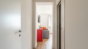 A narrow hallway with a red refrigerator, a gray sofa, and a white wall with a mounted picture. - Palazzo Ferrara Rooms by Wonderful Italy (Palermo)