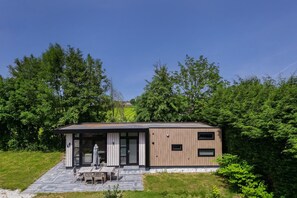 A modern house with a patio, a dining area, and a view of the surrounding greenery. - Lodge 18 | 4 persoons chalet in Zennewijnen (Zennewijnen)