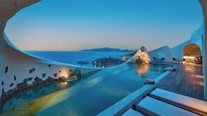 A poolside area with a view of the sea, stone walls, and a wooden deck. - Ibala Hotel & Spa (Bac Nha Trang)