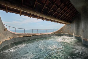 Uma fonte termal com uma plataforma de observação curva e teto de madeira.