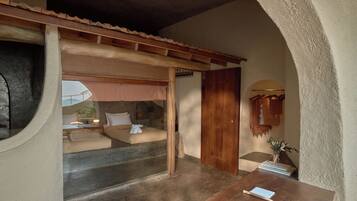 A room with a bed, a wooden table, and a small desk with a lamp.