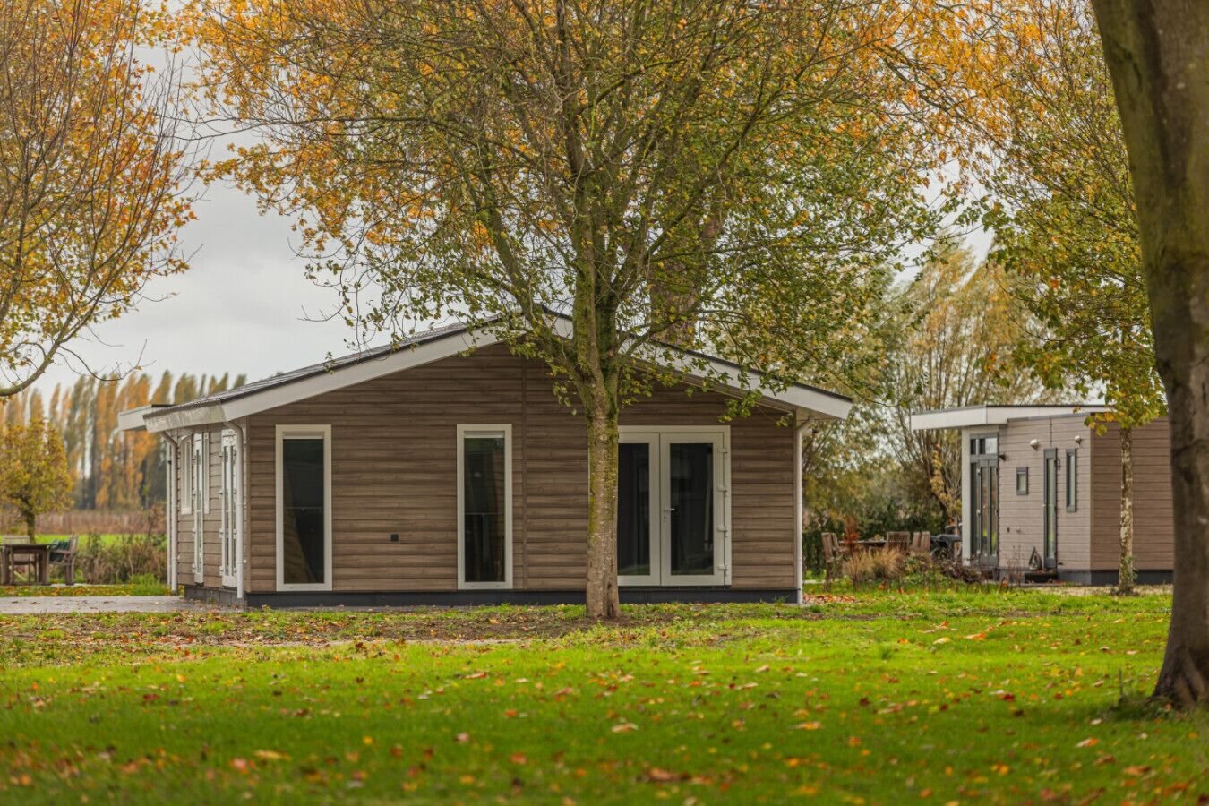 Une petite cabane en bois d’un seul étage, dotée d’un petit porche et entourée d’une pelouse et d’arbres.