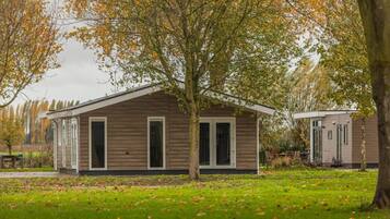 Une petite cabane en bois d’un seul étage, dotée d’un petit porche et entourée d’une pelouse et d’arbres.