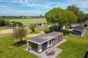 Un espace de vie extérieur moderne, comprenant un ensemble de mobilier de jardin, un grand arbre et une vue sur le paysage environnant.