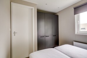 A bedroom with a bed, a wardrobe, and a window.