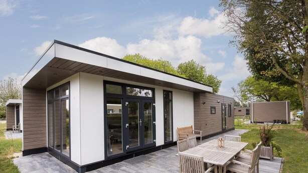 A modern building with a patio area, outdoor seating, and a clear sky.