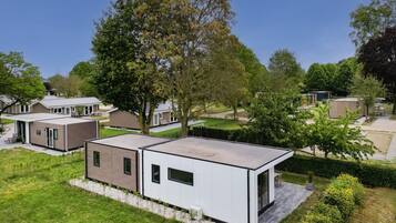 A modern residential area with detached houses, a flat roofed structure, and a well-maintained lawn.