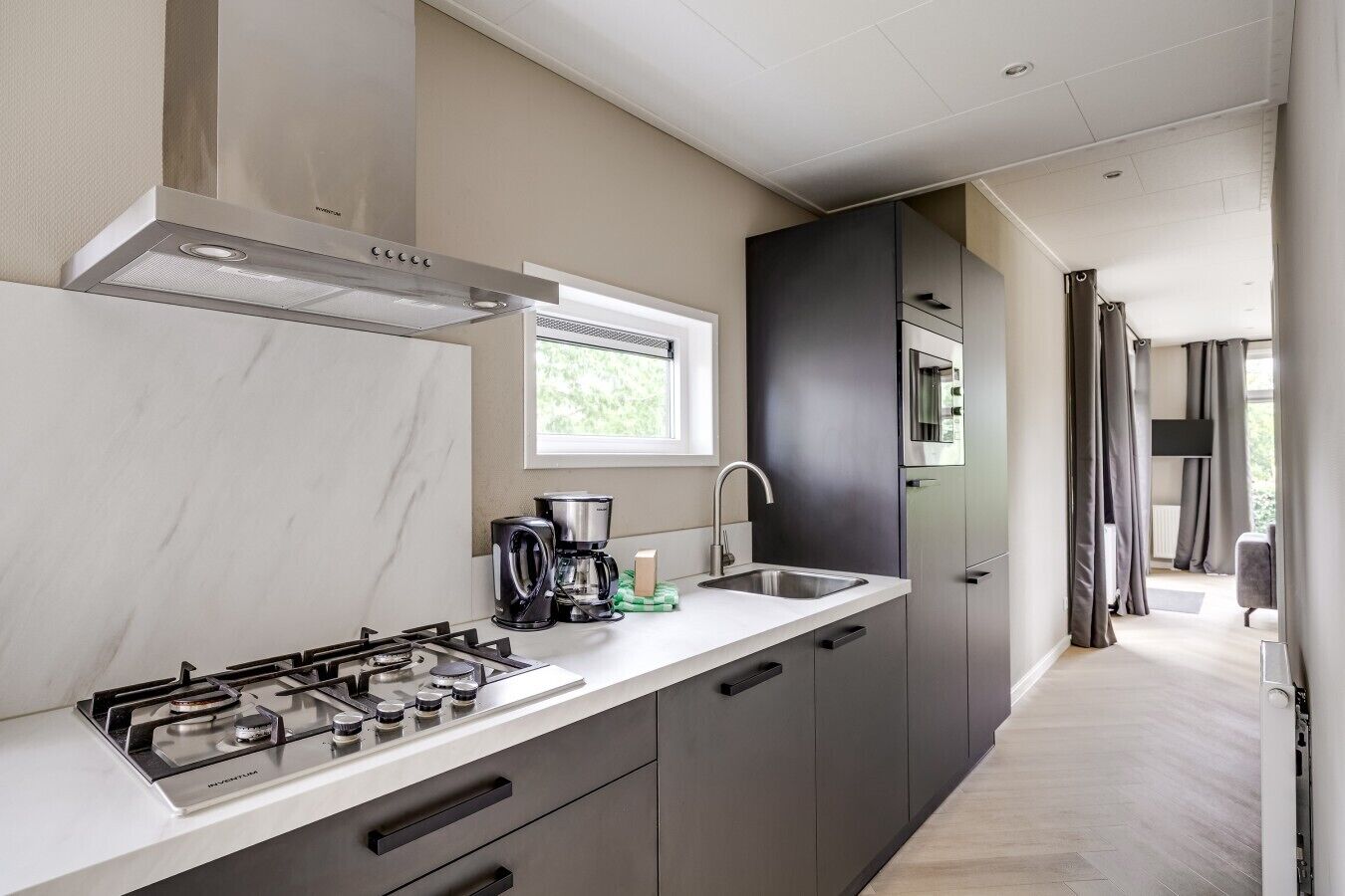 Une cuisine moderne équipée d’une cuisinière à gaz, d’une machine à café et d’une fenêtre.