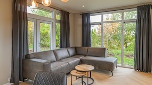 Ein modernes Wohnzimmer mit einem Ecksofa, einem runden Couchtisch und einem Esstisch.