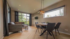 Ein geräumiges Zimmer mit einer Couch, einem Esstisch, Stühlen und einer Hängelampe.